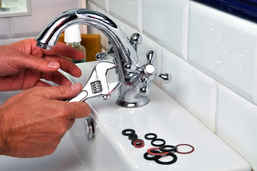 Plumber performing maintenance on a bathroom faucet in New Castle