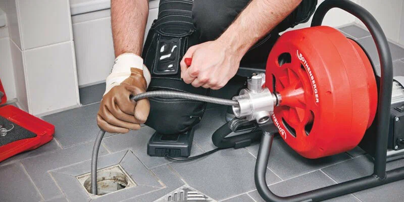 Plumber using a drain-cleaning machine in New Castle