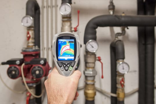 Plumber using a thermal imaging camera to inspect pipes in New Castle