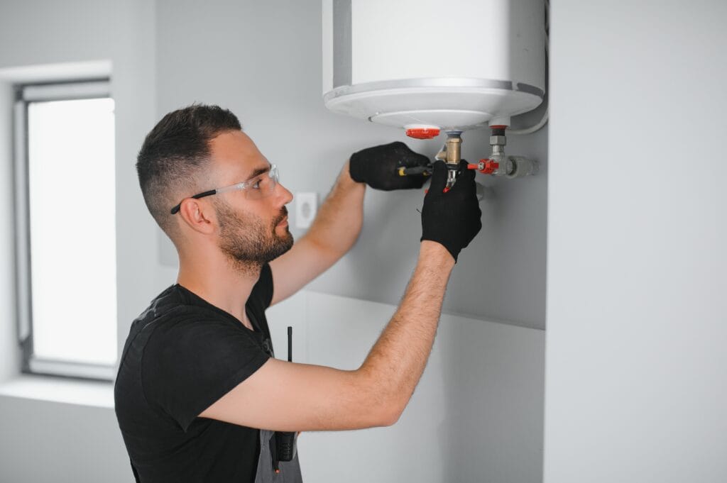 Technician performing water heater maintenance in New Castle