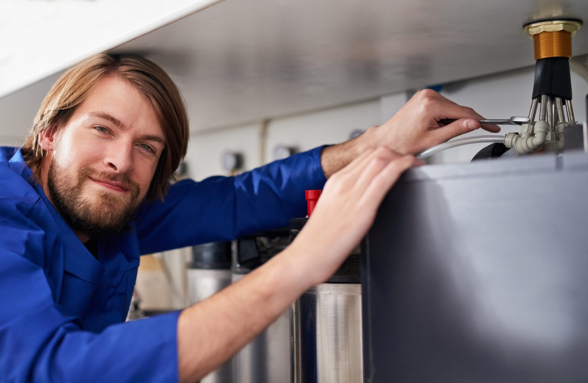 Technician servicing a residential water heater tank in New Castle
