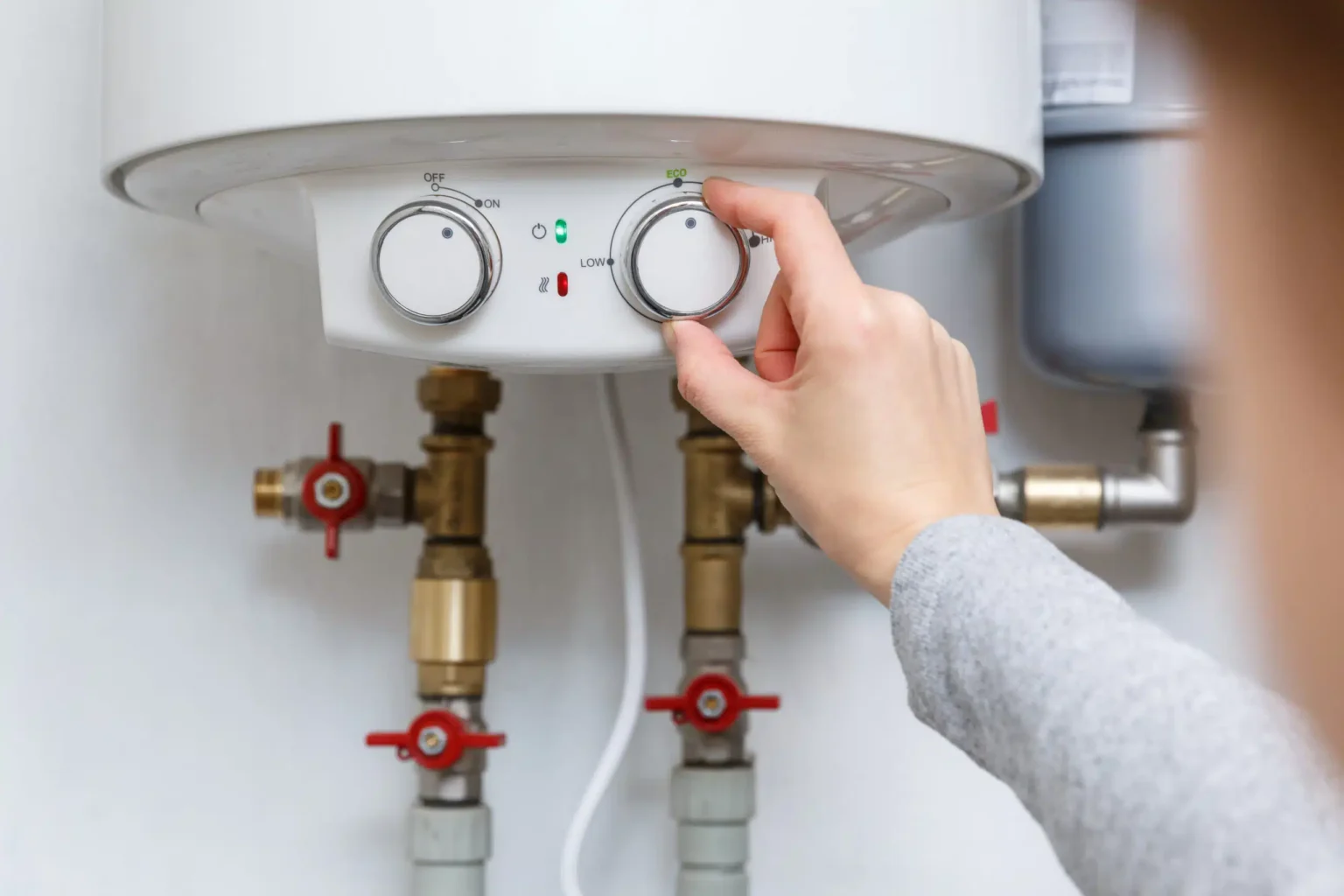 Homeowner adjusting the temperature controls on a water heater in New Castle